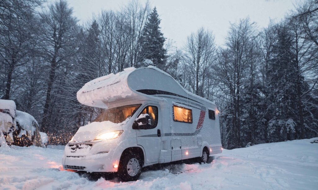 Alkoof camper in de sneeuw tussen de bomen